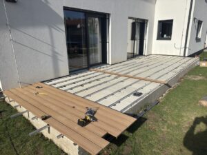Detail pokládky dřevoplastových prken na hliníkové nosiče na betonu.